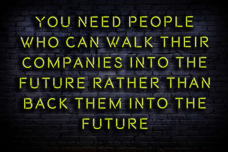 Wise quotation as light neon sign on brick wallの写真素材