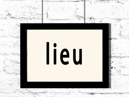 Black wooden frame with inscription lieu hanging on white brick wallの写真素材