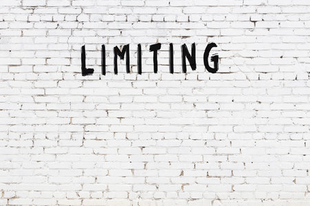 White brick wall with inscription limiting handwritten with black paintの写真素材