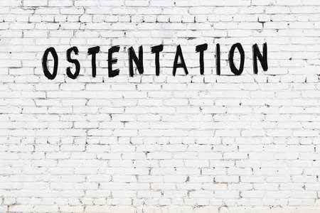 White brick wall with inscription ostentation handwritten with black paintの写真素材