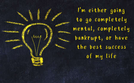 Wise quotation and a chalk drawing of a bulb on black chalkboardの写真素材