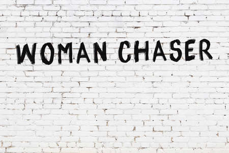 White brick wall with inscription woman chaser handwritten with black paintの写真素材