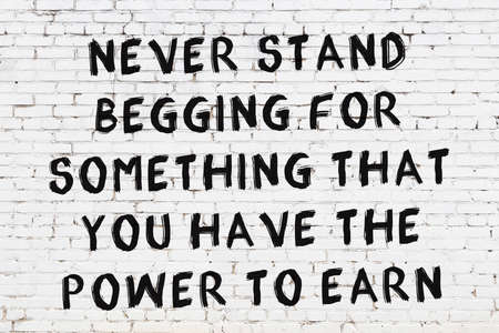 Black painted inscription of smart quotation on white brick wallの写真素材