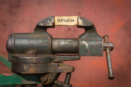 Concept of dealing with problem. Vice grip tool squeezing a plank with the word fabricationの写真素材