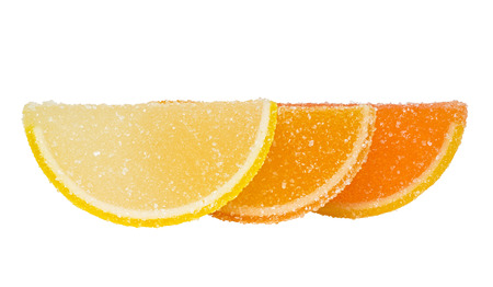 Three slices of yellow and orange marmalade sprinkled with sugar, stand one behind another, and are located on a white background.の写真素材