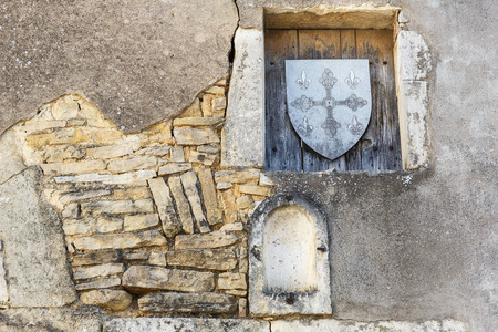 Old stone wall with niches and wooden shield stamp in one of the cities in Burgundy, Franceの写真素材