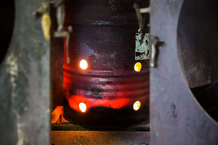 Red-hot iron barrel in which wood waste is burned to heat the production roomの写真素材