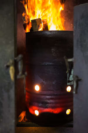 Red-hot steel barrel with bright open flame boards for heating the production roomの写真素材