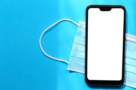 Mask and smartphone with an isolated white screen to insert an inscription, text or image on a blue...