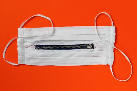 White unusual medical mask with a zipper on an orange background.