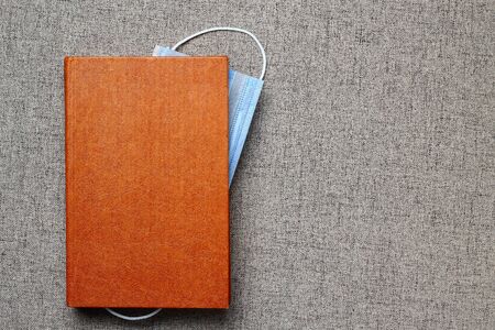 A medical or surgical mask acts as a bookmark in a book. With space for lettering or text. The...