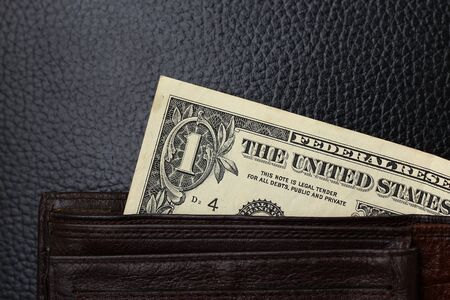 1 dollar from a brown wallet on a black leather sofaの写真素材