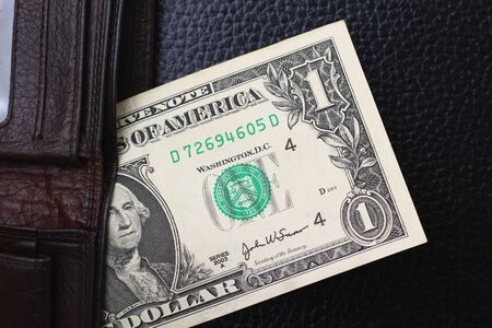 1 dollar from a brown wallet on a black leather backgroundの写真素材