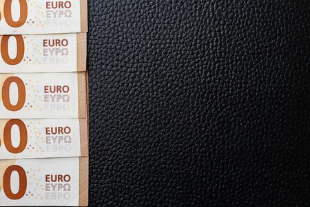 Zeros of euros on a black leather texture luxury background, the concept of losses and lack of profit and profitabilityの写真素材