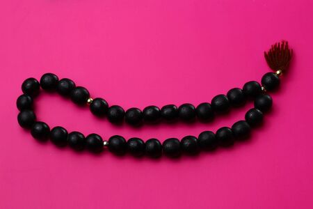 Black wooden rosary in on a pink backgroundの写真素材