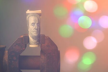 US dollars sandwiched in an old vice, toned