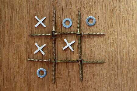 Resourcefulness and creativity in the organization of the game. Tic tac toe. Improvised attributes: screws, washers and crosses for laying tileの写真素材