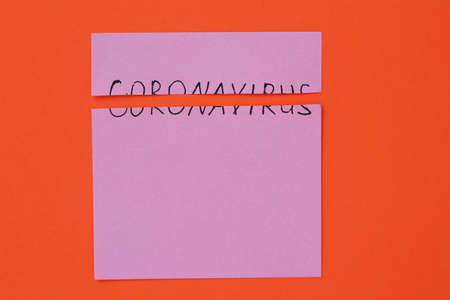The inscription on the sticker Coronavirus torn in half on an orange backgroundの写真素材