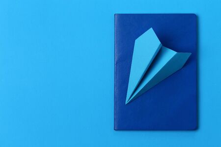 Airplane made of paper and passport on a blue background with copy space for placing an inscription...