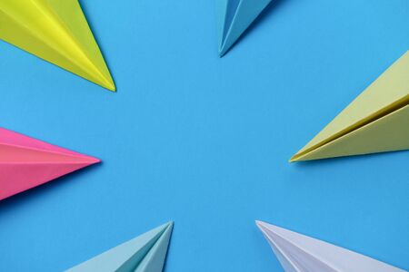 Multicolored noses of paper airplanes on a blue background with place for text.の写真素材
