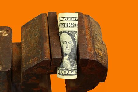 Dollar clamped in a vice. The concept of the global financial crisis and economic contraction. Orange backgroundの写真素材