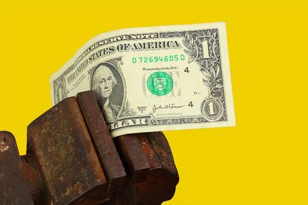 Dollar clamped in a vice. The concept of the global financial crisis and economic contraction. Yellow backgroundの写真素材