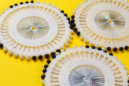 Pins or needles with a pearl on a round tablet. Bright background. Hobby and sewing