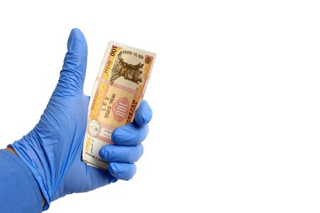 A hand in a medical glove holds the money of the state of the Republic of Moldova, lei, on a white...