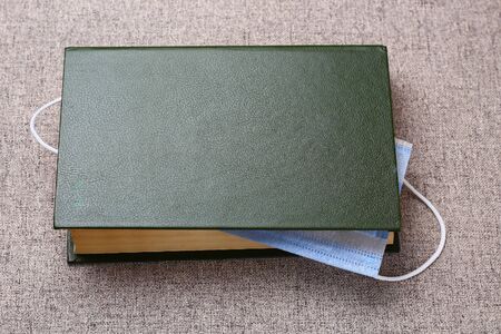 A medical or surgical mask acts as a bookmark in a book. With space for lettering or text. The...