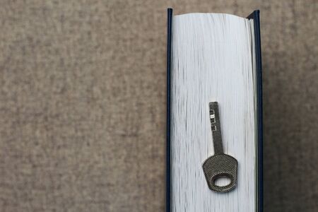 Classic key on a book background. Symbol of the discovery of knowledgeの写真素材