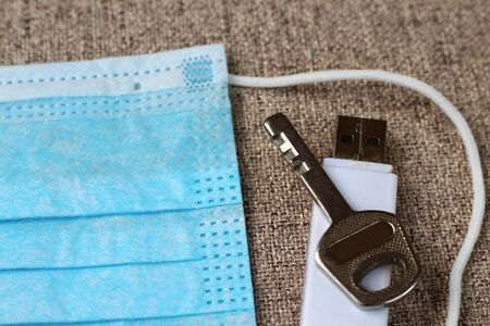 Key and flash drive lie on a medical surgical mask, medical secret concept