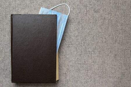 A medical or surgical mask acts as a bookmark in a book. With space for lettering or text. The...