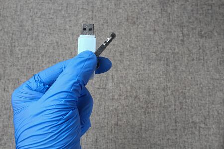 A key and a flash drive in a hand wearing a medical glove. Medical Secret Conceptの写真素材