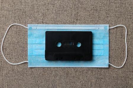 Audio cassette and medical surgical mask, abstract concept of nostalgia for music and concerts under...
