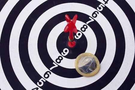 Unpacked condom on the background of a dartboard target darts tonedの写真素材