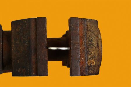 Coin in a vice on an orange background, tonedの写真素材
