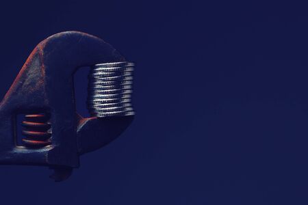 Adjustable wrench compresses coins with copy space for inscription or text, tonedの写真素材