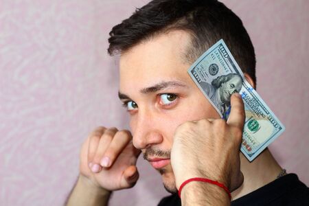 A young man covers his ears with dollars. Concept heard nothing for money