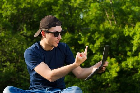 A man shows the middle finger to the laptop camera. Concept of extreme discontent