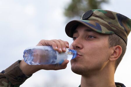 The soldier drinks water from a plastic bottleの写真素材