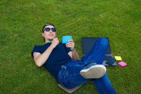 Freelancer lies on a green lawn with a laptopの写真素材
