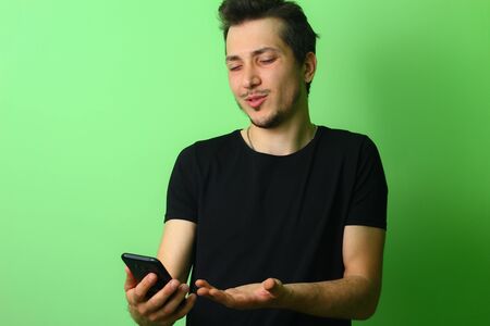 Young displeased man expresses emotion of discontent on a green background