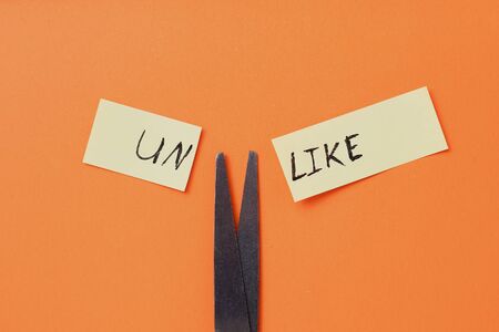 The inscription on the sticker: UNLIKE cut in half on an orange backgroundの写真素材