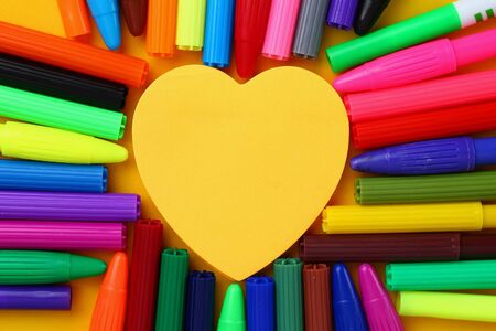 Sticker in the shape of a heart surrounded by multi-colored markers. Space for inscription or text.の写真素材