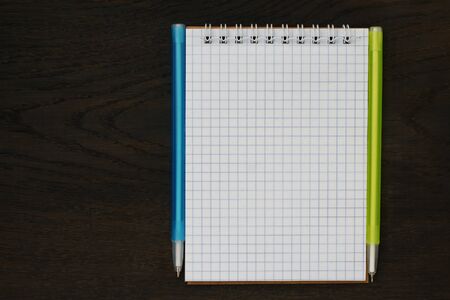 Open blank notebook and two pens. Mockup with copy space. Wood background