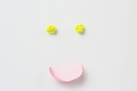 Abstract happy Emoticon made of crumpled paper on a white wooden backgroundの写真素材