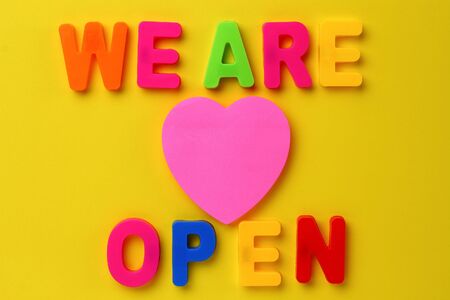 Text made in multicolored magnetic letters. WE ARE OPEN. Yellow backgroundの写真素材
