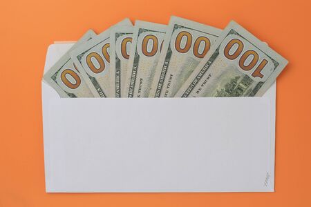 Classic white new mail envelope with dollars inside on an orange background. Copy space for textの写真素材