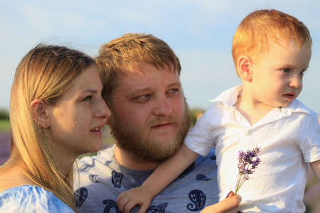 Lifestyle photo shoot of a real family in nature. Mom, dad and son enjoy a walk through the fresh...