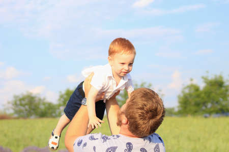 Lifestyle photo shoot of a real family in nature. Dad and son enjoy a stroll through the fresh air in the rays of the setting sun. Selective focusの写真素材